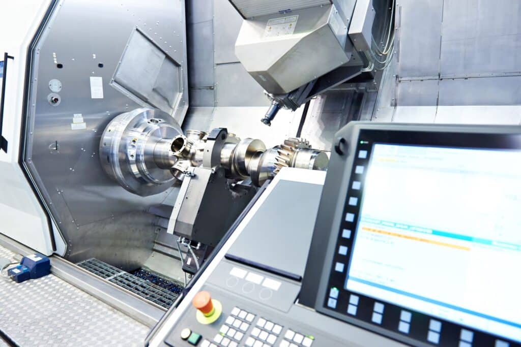 Moderne CNC-Fräsmaschine bei der Präzisionsbearbeitung eines metallischen Werkstücks, mit Bedienfeld im Vordergrund und hochentwickelter Maschinentechnologie im Einsatz