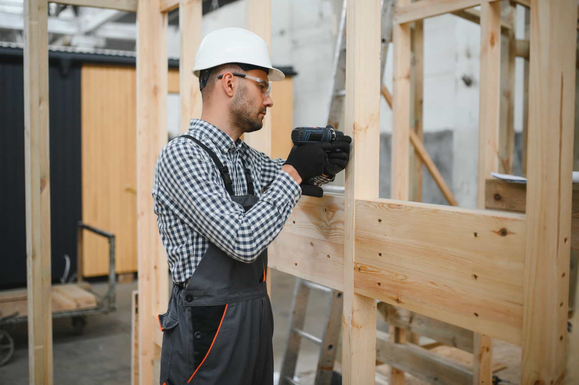 Ein Handwerker montiert eine Holzkonstruktion, die als Basis für flexible Raumlösungen wie ein Lagerzelt dienen könnte.