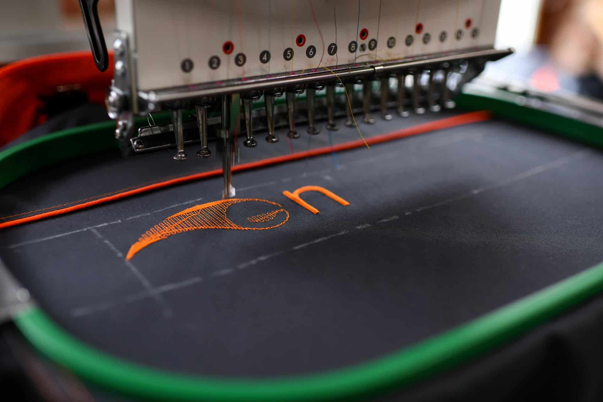 Stickmaschine bestickt dunklen Stoff mit Logo