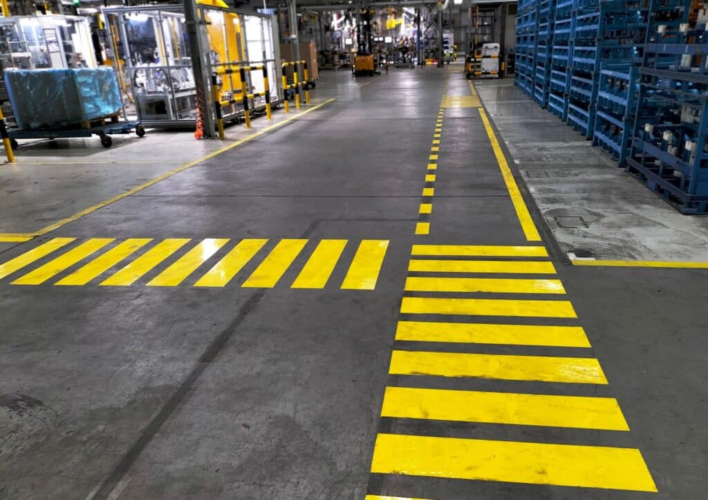 Gelbe Bodenmarkierung in einer modernen Industriehalle zur Trennung von Laufwegen und Verkehrsbereichen