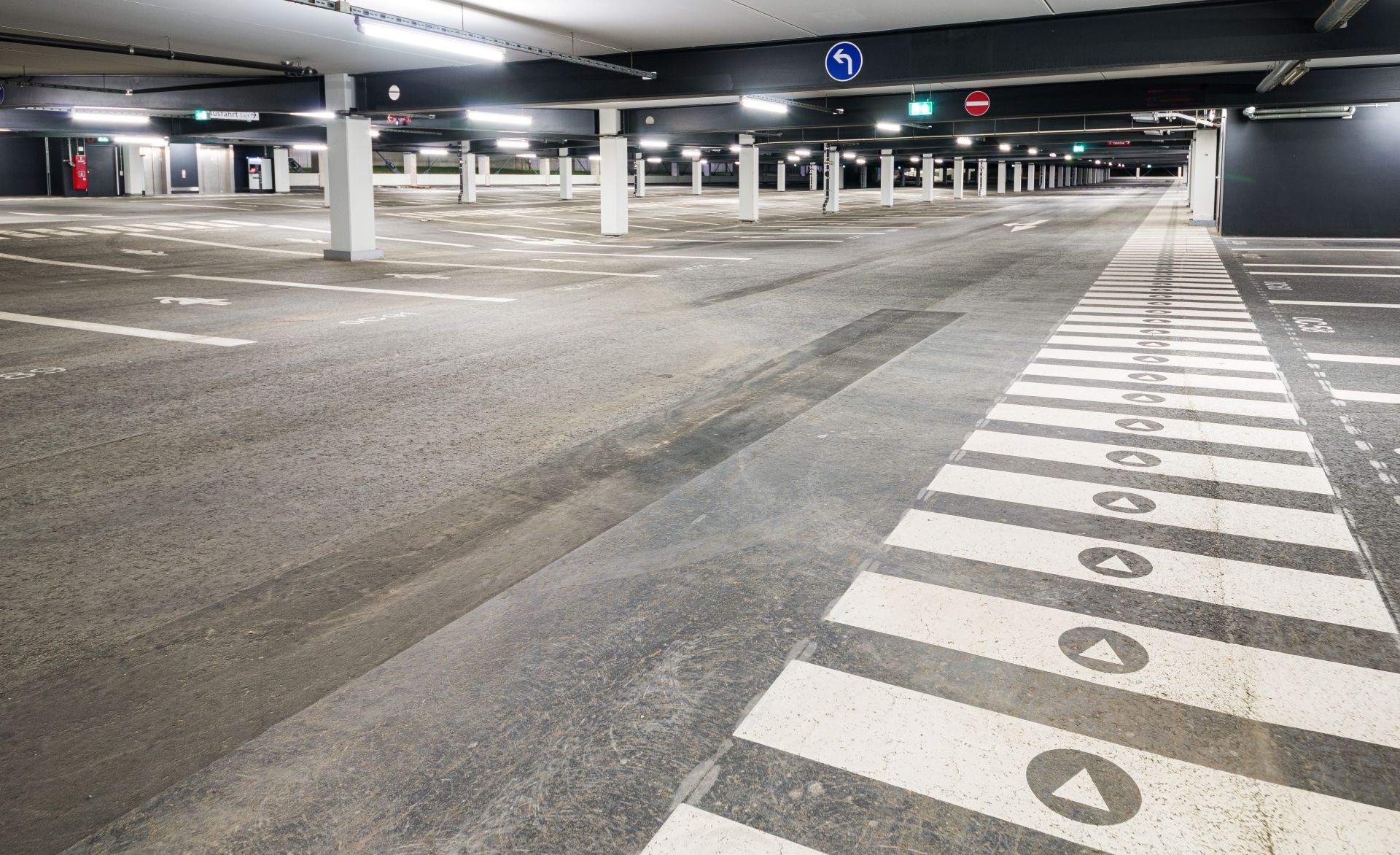 Strukturierte Bodenmarkierungen in einer leeren Tiefgarage mit sichtbaren Fahr- und Gehwegen