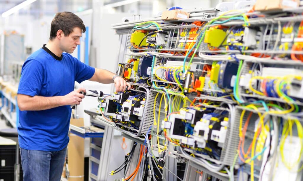 Kabelkonfektionierung an einem Elektroarbeitsplatz mit präziser Handarbeit an einem komplexen Leitungssystem