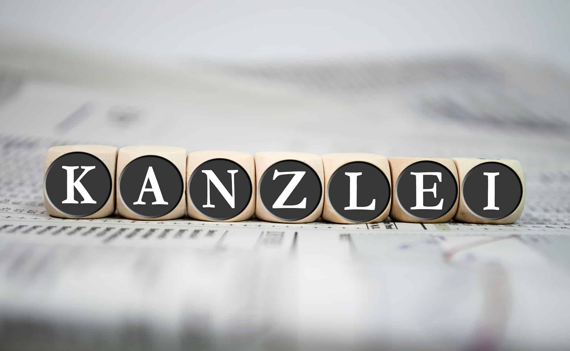 Holzwürfel bilden das Wort Kanzlei auf Zeitung | Rechtsanwaltsfachangestellte Würzburg
